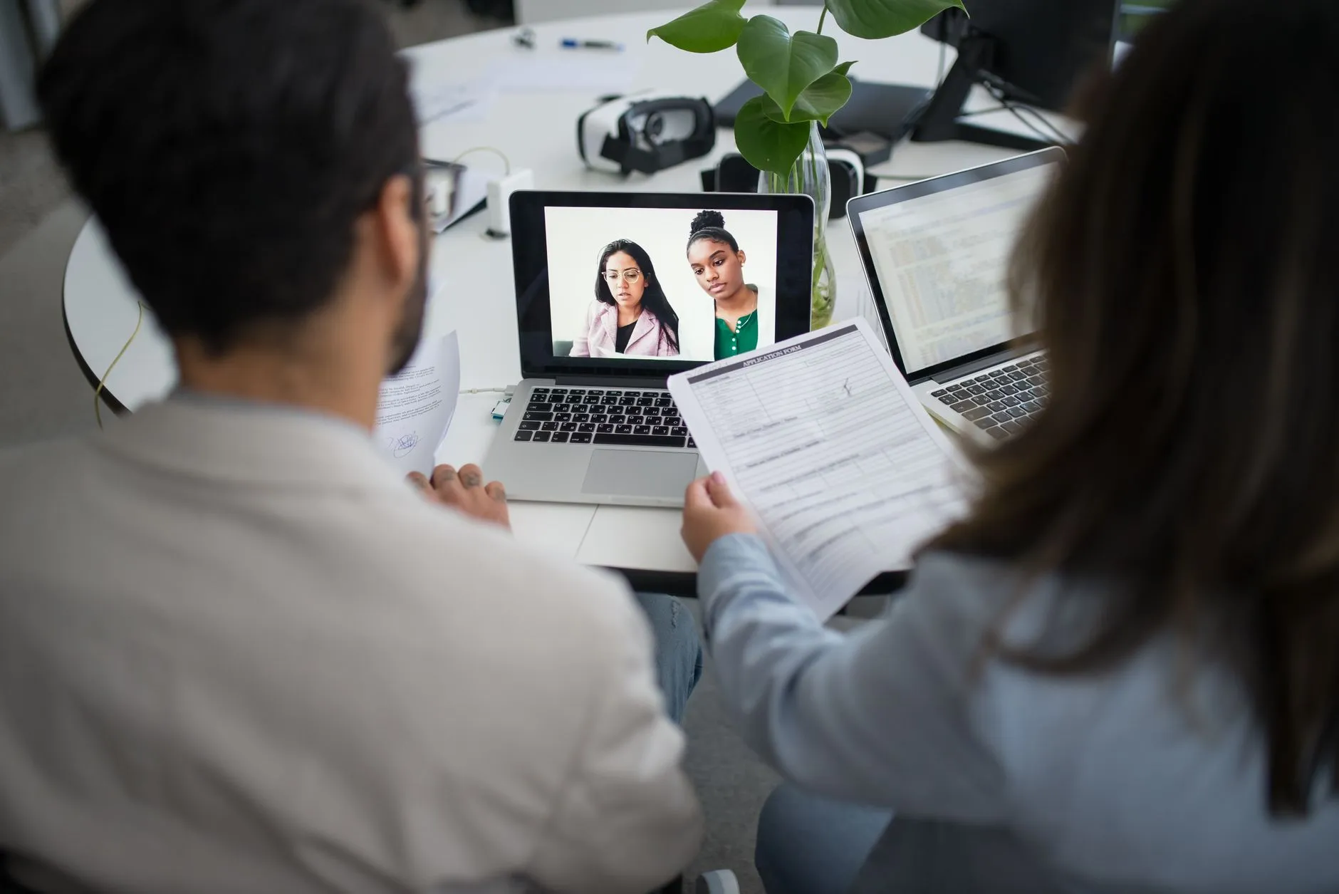 Candidata em entrevista por videochamada, com uma recrutadora e um currículo na mão