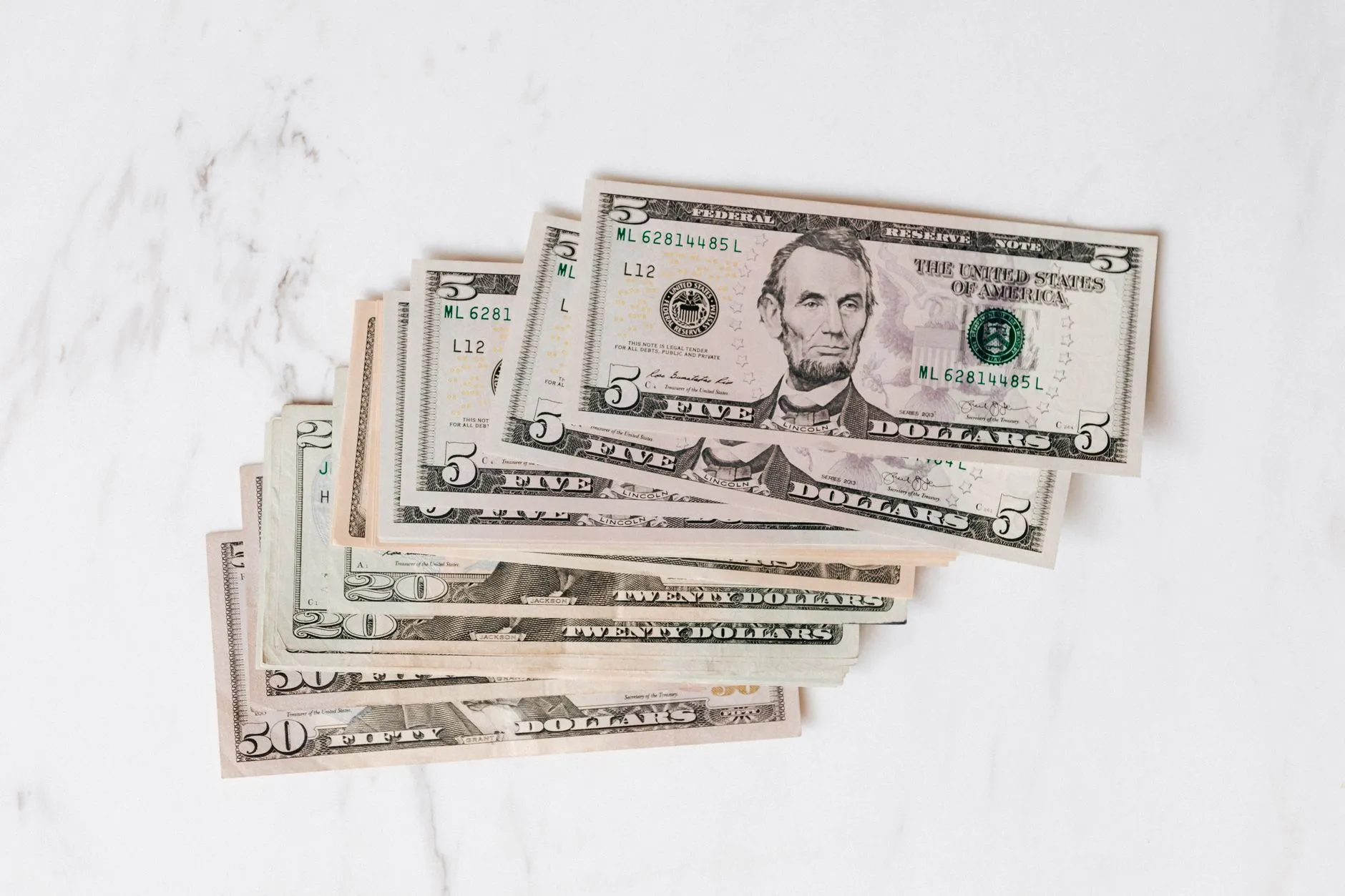 Notas de dólar em leque sobre uma superfície de mármore