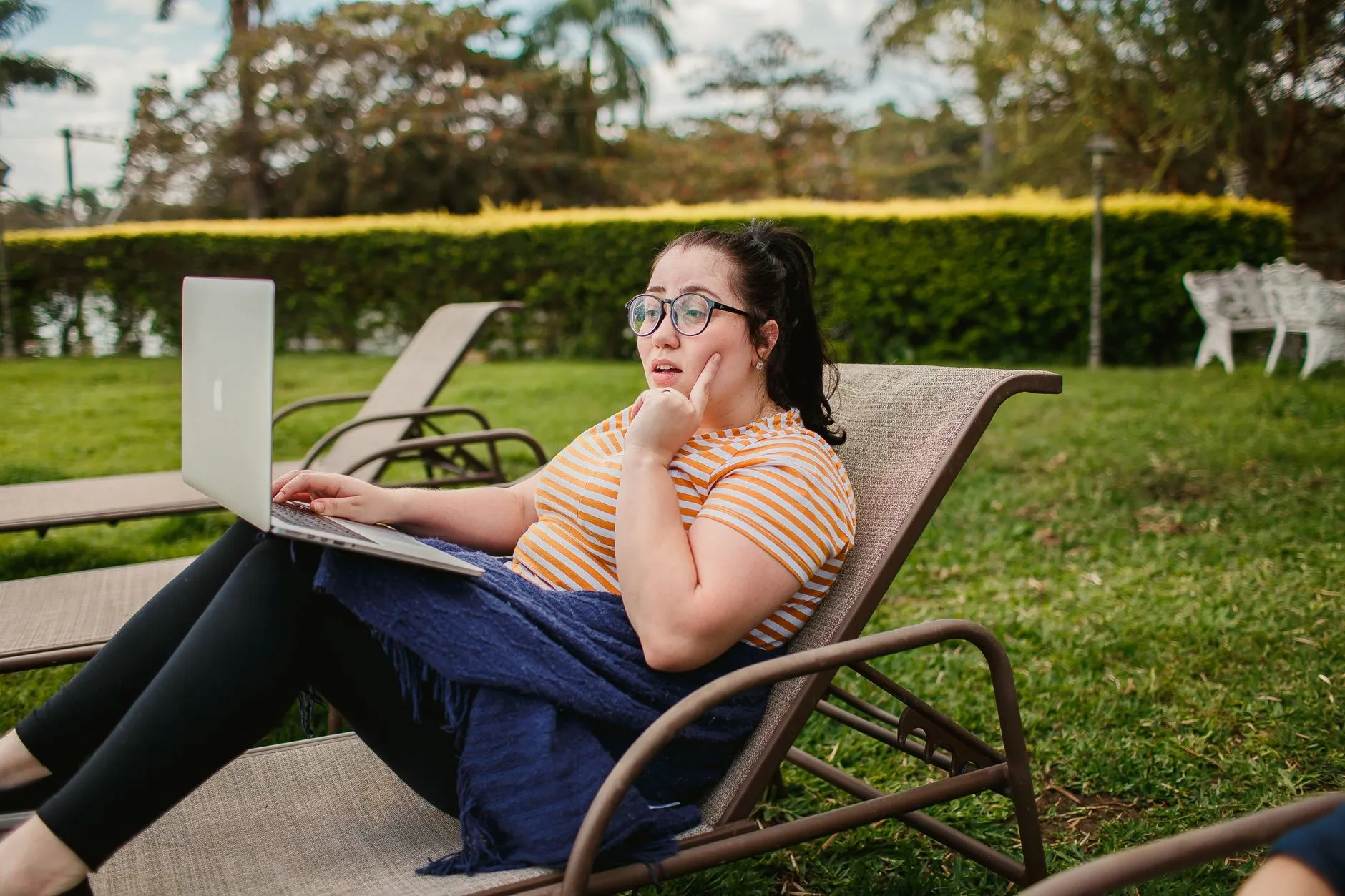 Jovem trabalhando no notebook em uma cadeira de jardim