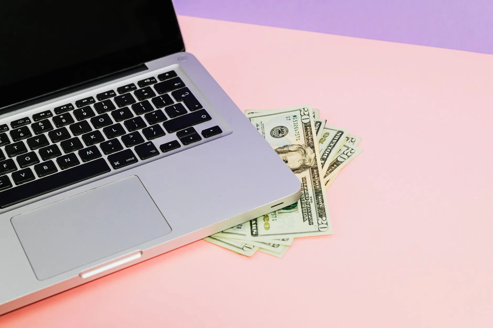 Notas de dólar ao lado de um notebook aberto sobre a mesa