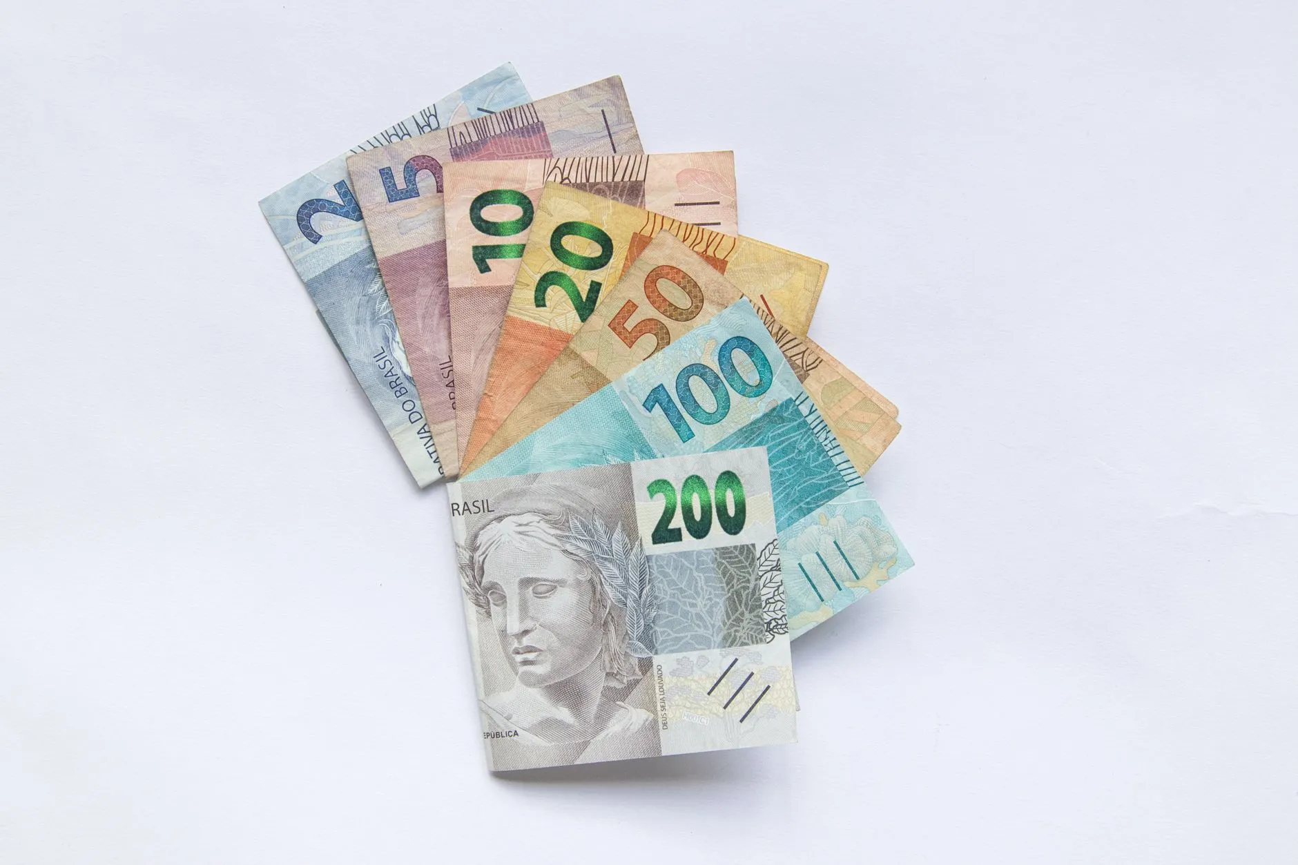Notas de real brasileiro de vários valores em leque sobre fundo branco